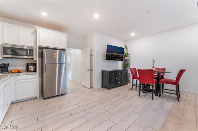 7107 Calvert Cliffs St, North Las Vegas, NV 89084 - kitchen featuring stainless steel appliances, white cabinetry, light wood-style flooring, light stone counters, and recessed lighting