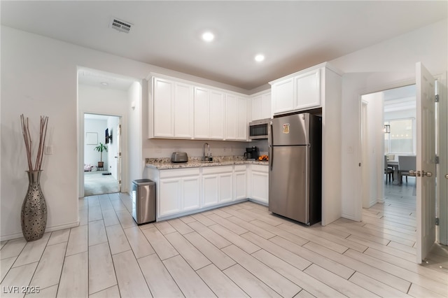 7107 Calvert Cliffs St, North Las Vegas, NV 89084 - kitchen featuring stainless steel appliances, a sink, white cabinets, light stone countertops, and recessed lighting