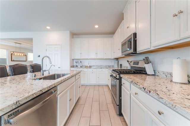 7107 Calvert Cliffs St, North Las Vegas, NV 89084 - kitchen with appliances with stainless steel finishes, a sink, white cabinetry, light stone countertops, and recessed lighting