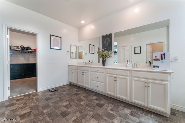 7107 Calvert Cliffs St, North Las Vegas, NV 89084 - bathroom with stone finish flooring, double vanity, baseboards, a walk in closet, and recessed lighting