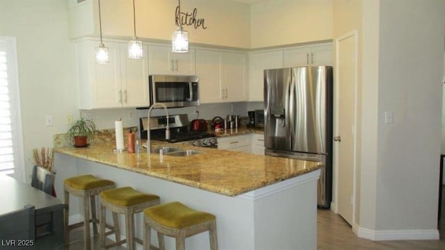 4821 Black Bear Rd Unit 104, Las Vegas, NV 89149 - kitchen featuring stainless steel appliances, a peninsula, light stone counters, white cabinetry, and baseboards