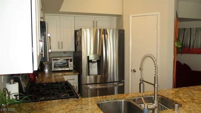 4821 Black Bear Rd Unit 104, Las Vegas, NV 89149 - kitchen featuring stainless steel fridge with ice dispenser, a sink, light stone countertops, white cabinets, and gas range