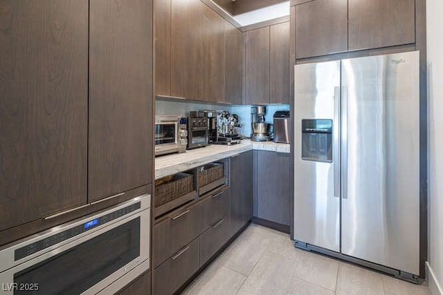 4070 N Tee Pee Ln, Las Vegas, NV 89129 - kitchen with appliances with stainless steel finishes, light countertops, dark brown cabinets, light tile patterned floors, and modern cabinets