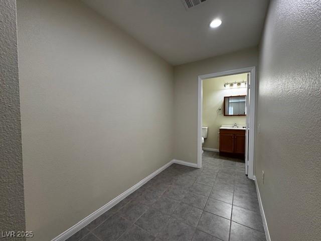 4189 Studio St, Las Vegas, NV 89115 - hallway with baseboards, dark tile patterned flooring, a sink, and recessed lighting