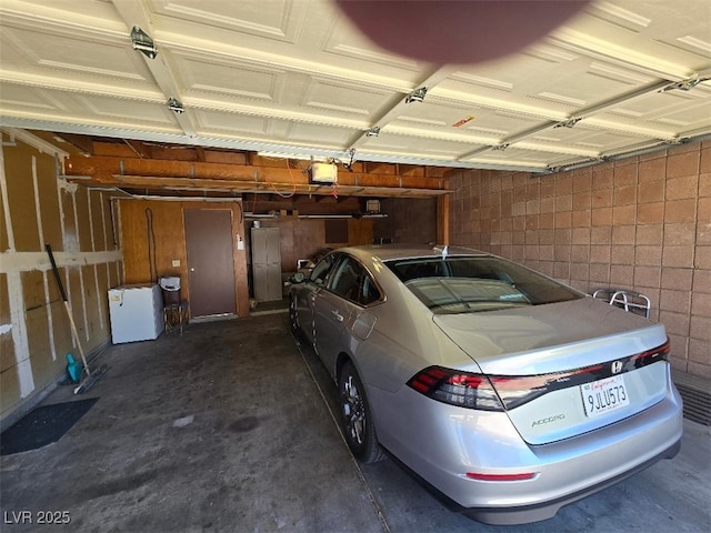 3660 Haverhill St, Las Vegas, NV 89121 - garage featuring a garage door opener, concrete block wall, and refrigerator