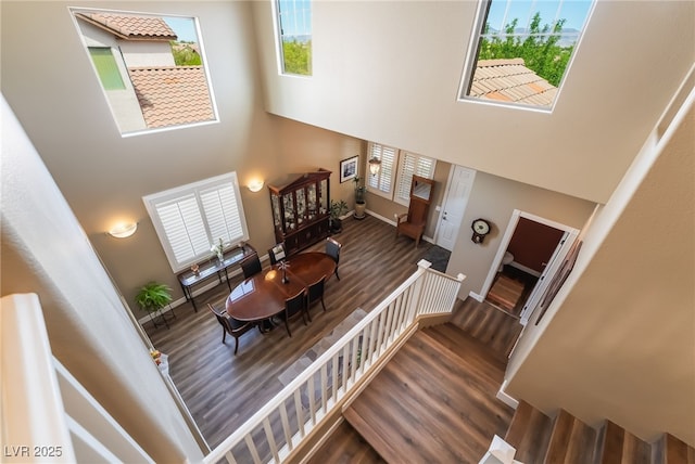 staircase with a towering ceiling, wood finished floors, and baseboards