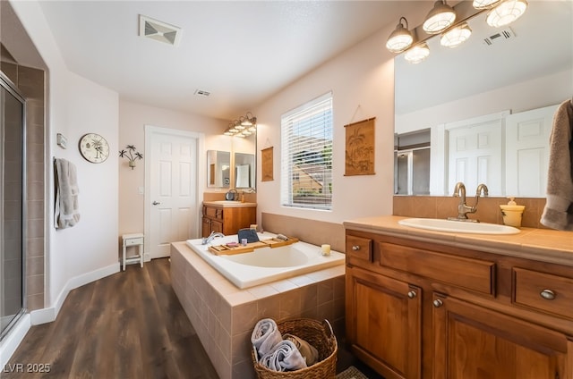 bathroom with a stall shower, wood finished floors, and a bath