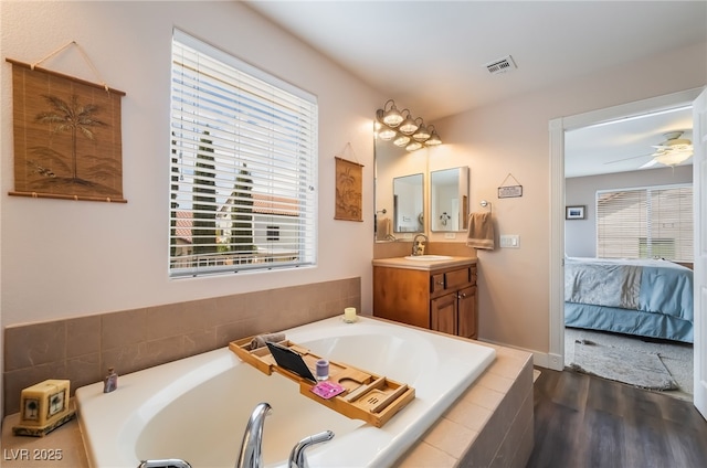 ensuite bathroom with wood finished floors, a bath, and vanity
