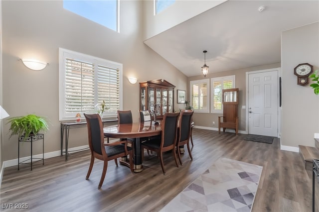 dining space featuring wood finished floors, baseboards, and a high ceiling