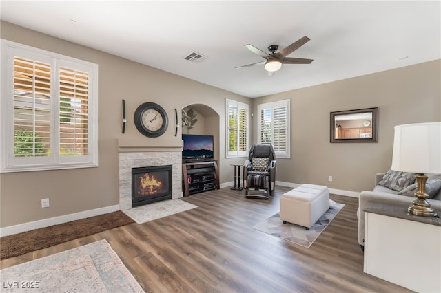 living area with ceiling fan, baseboards, wood finished floors, and a fireplace