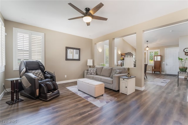 living room with a ceiling fan, baseboards, and dark wood finished floors