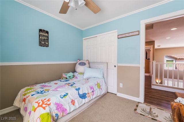carpeted bedroom with a closet, baseboards, a ceiling fan, and ornamental molding