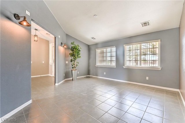 tiled empty room featuring baseboards and vaulted ceiling