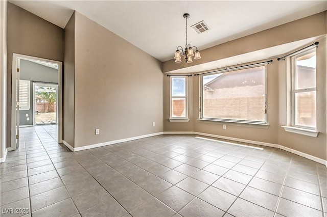 tiled empty room featuring a chandelier and baseboards