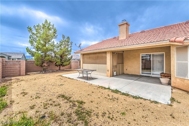 back of property featuring a chimney, stucco siding, a fenced backyard, and a patio