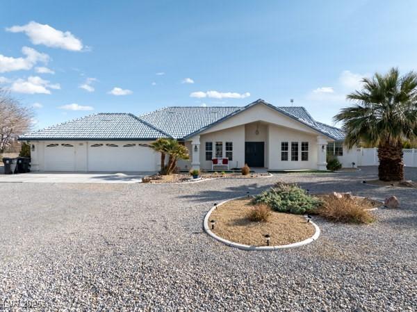1251 Cavalry St, Pahrump, NV 89048 - ranch-style home featuring driveway, an attached garage, a tile roof, and stucco siding