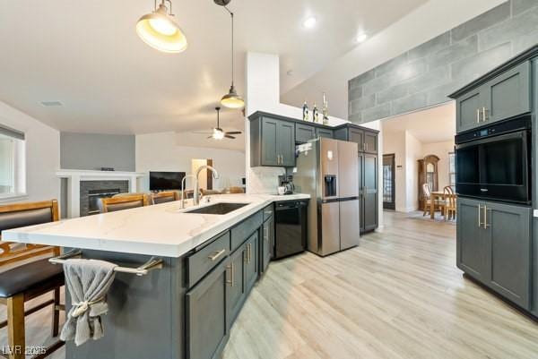 1251 Cavalry St, Pahrump, NV 89048 - kitchen featuring black appliances, a sink, a peninsula, light wood-style floors, and a fireplace