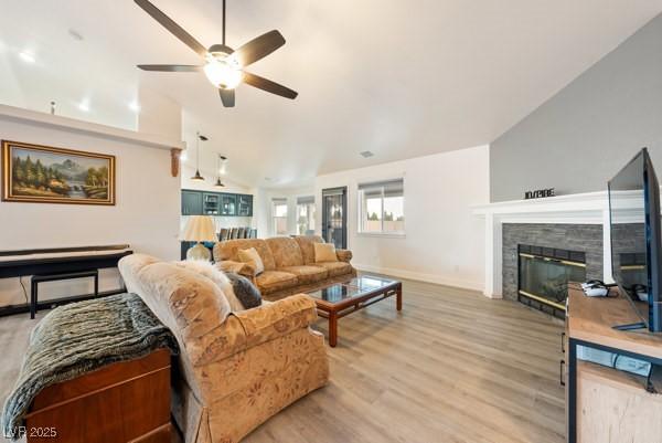 1251 Cavalry St, Pahrump, NV 89048 - living room featuring lofted ceiling, ceiling fan, light wood-style flooring, baseboards, and a tiled fireplace