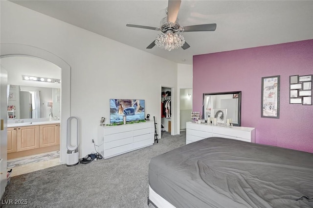 bedroom featuring arched walkways, light colored carpet, ceiling fan, ensuite bathroom, and vaulted ceiling