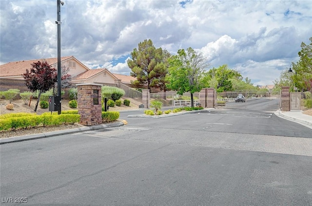 view of asphalt street featuring a gate, curbs, and a gated entry