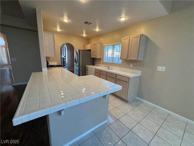 3136 Jane Austin Ave, North Las Vegas, NV 89031 - kitchen with white dishwasher, tile countertops, stainless steel fridge with ice dispenser, arched walkways, and a peninsula