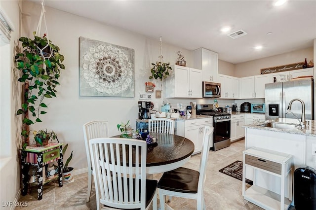 5236 Sunstone Mesa Dr, Las Vegas, NV 89166 - kitchen with stainless steel appliances, a sink, light stone countertops, white cabinetry, and recessed lighting