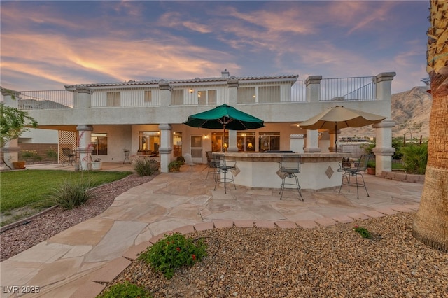 6999 Stone Meadows Ave, Las Vegas, NV 89142 - back of property at dusk featuring stucco siding, a patio area, and a balcony