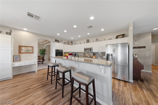6999 Stone Meadows Ave, Las Vegas, NV 89142 - kitchen with appliances with stainless steel finishes, arched walkways, light wood-style floors, recessed lighting, and a breakfast bar