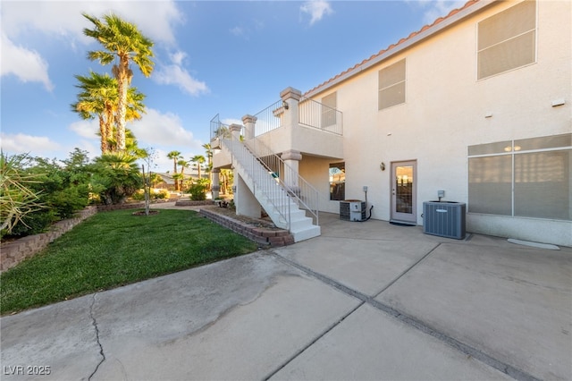 6999 Stone Meadows Ave, Las Vegas, NV 89142 - rear view of house with central air condition unit, stucco siding, a patio area, a yard, and stairs