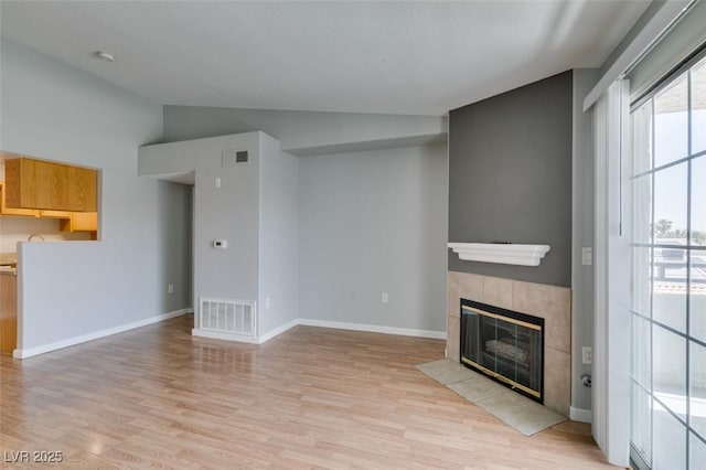 3318 N Decatur Blvd Unit 2110, Las Vegas, NV 89130 - unfurnished living room with a tiled fireplace, lofted ceiling, light wood-style flooring, and baseboards