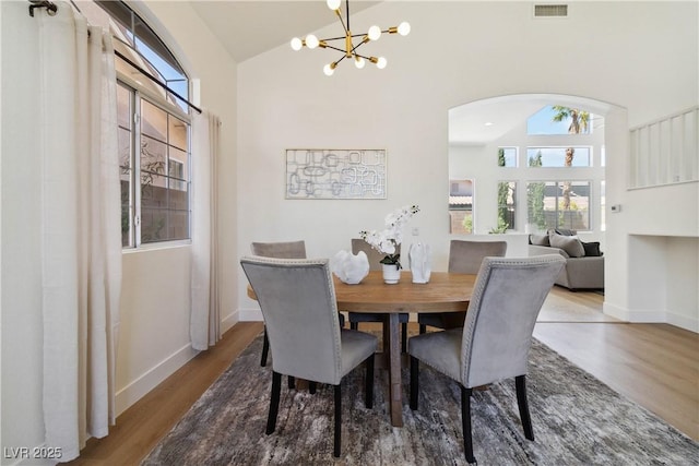 8714 Las Posas Ave, Las Vegas, NV 89147 - dining space with wood finished floors, a chandelier, arched walkways, high vaulted ceiling, and baseboards