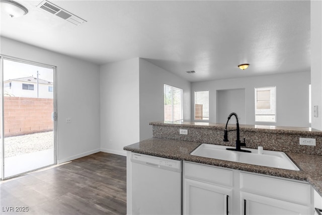4149 Dignified Ct, North Las Vegas, NV 89032 - kitchen featuring white dishwasher, a sink, white cabinets, dark stone countertops, and wood finished floors