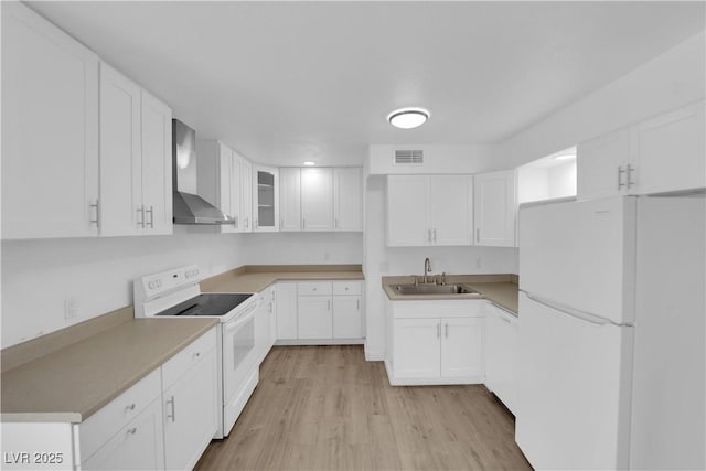 721 Carpenter Dr, Las Vegas, NV 89107 - kitchen with white appliances, wall chimney range hood, a sink, light wood-style flooring, and white cabinets