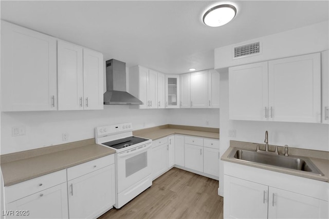 721 Carpenter Dr, Las Vegas, NV 89107 - kitchen featuring white electric range oven, wall chimney range hood, a sink, light wood-style floors, and white cabinets