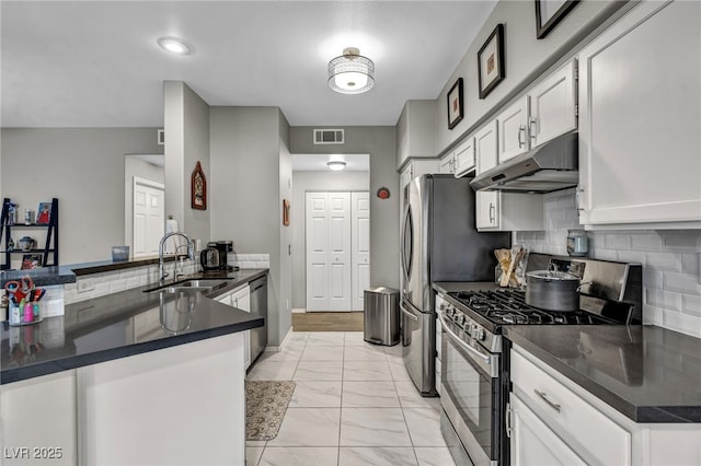 8501 W University Ave Unit 1083, Las Vegas, NV 89147 - kitchen with stainless steel appliances, under cabinet range hood, a sink, dark countertops, and a peninsula
