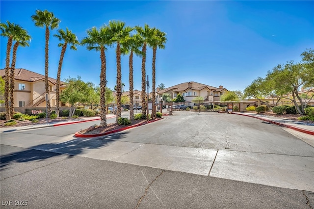 8501 W University Ave Unit 1083, Las Vegas, NV 89147 - view of asphalt road with a residential view, sidewalks, curbs, a gate, and a gated entry