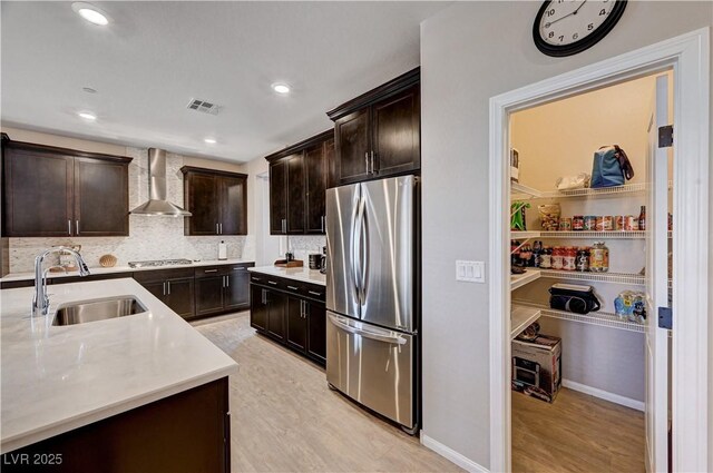 2902 Ventana Ridge Ave, Henderson, NV 89044 - kitchen with freestanding refrigerator, wall chimney range hood, a sink, light countertops, and dark brown cabinetry