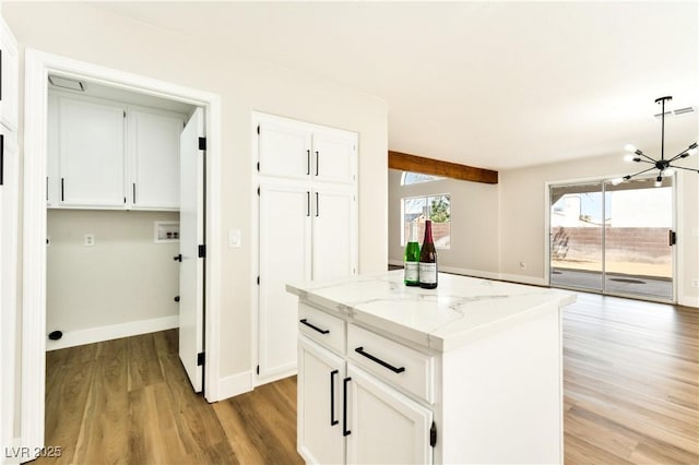 1724 Navajo Lake Way, Las Vegas, NV 89128 - kitchen with light wood finished floors, a chandelier, light stone counters, white cabinets, and a kitchen island