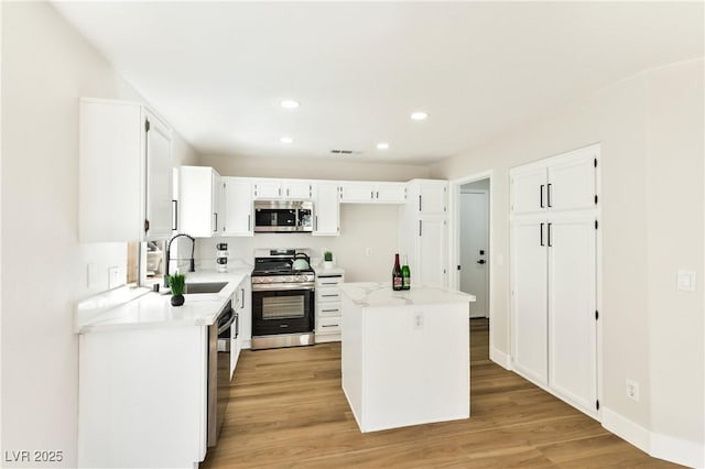 1724 Navajo Lake Way, Las Vegas, NV 89128 - kitchen with stainless steel appliances, a sink, light wood-type flooring, white cabinets, and recessed lighting