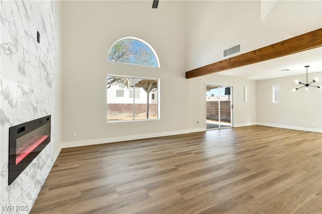 1724 Navajo Lake Way, Las Vegas, NV 89128 - unfurnished living room featuring a glass covered fireplace, a chandelier, wood finished floors, baseboards, and a towering ceiling