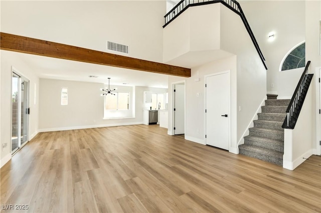 1724 Navajo Lake Way, Las Vegas, NV 89128 - unfurnished living room featuring a chandelier, stairs, a towering ceiling, light wood-type flooring, and baseboards