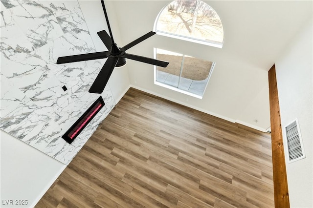 1724 Navajo Lake Way, Las Vegas, NV 89128 - unfurnished living room featuring wood finished floors, a ceiling fan, a warm lit fireplace, and healthy amount of natural light