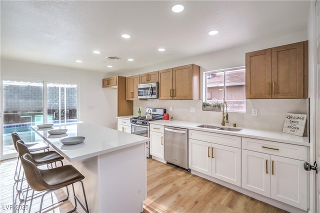 5239 Elgin Cir, Las Vegas, NV 89122 - kitchen with appliances with stainless steel finishes, a sink, a breakfast bar, light countertops, and recessed lighting