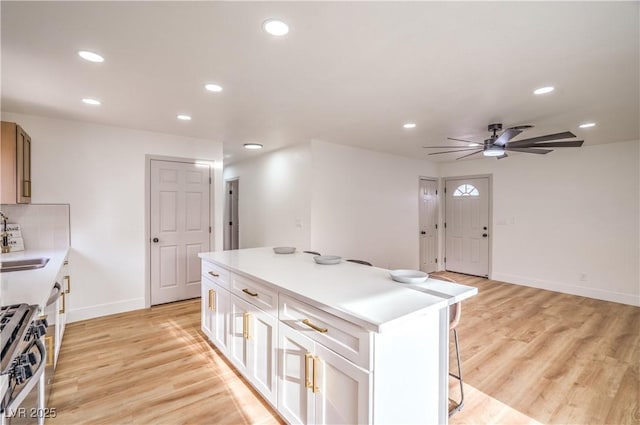 5239 Elgin Cir, Las Vegas, NV 89122 - kitchen with stainless steel gas range oven, a breakfast bar, recessed lighting, baseboards, and a ceiling fan