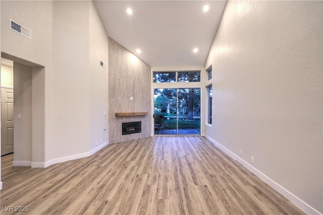 5010 Crooked Stick Way, Las Vegas, NV 89113 - unfurnished living room featuring wood finished floors, a tiled fireplace, baseboards, recessed lighting, and a towering ceiling