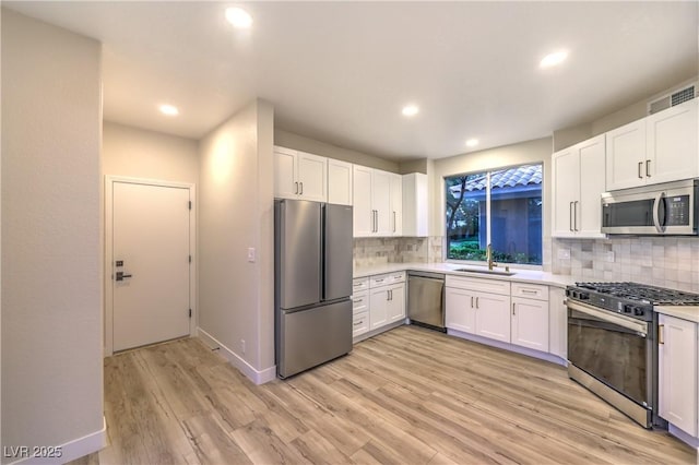 5010 Crooked Stick Way, Las Vegas, NV 89113 - kitchen with appliances with stainless steel finishes, a sink, decorative backsplash, light countertops, and light wood-style floors