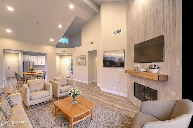 5010 Crooked Stick Way, Las Vegas, NV 89113 - living room featuring high vaulted ceiling, baseboards, light wood-type flooring, a large fireplace, and beam ceiling