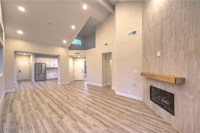 5010 Crooked Stick Way, Las Vegas, NV 89113 - unfurnished living room featuring high vaulted ceiling, a tiled fireplace, baseboards, light wood-style flooring, and beamed ceiling