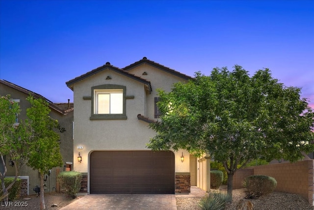 2276 Sky Island Dr, Henderson, NV 89002 - mediterranean / spanish-style home featuring stucco siding, a garage, decorative driveway, stone siding, and a tile roof