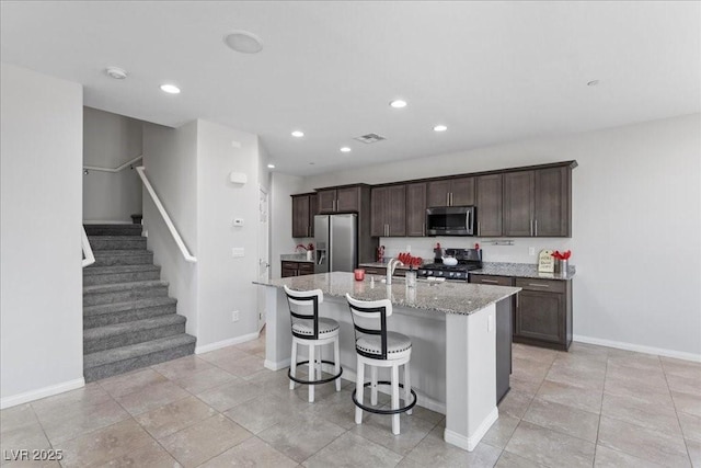 2276 Sky Island Dr, Henderson, NV 89002 - kitchen with stainless steel appliances, an island with sink, recessed lighting, dark brown cabinetry, and a kitchen breakfast bar